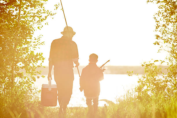 Shot of a father helping his son to reel in a fish