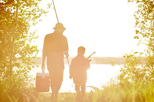 Father with son and daughter on fishing together outdoors at summertime.