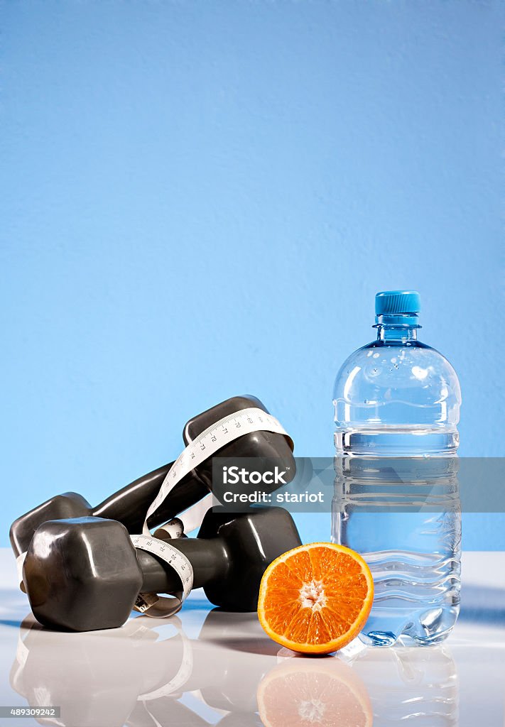 Oranges, weights and bottлѓe of water Oranges, weights and botte of water isolate on blue background 2015 Stock Photo