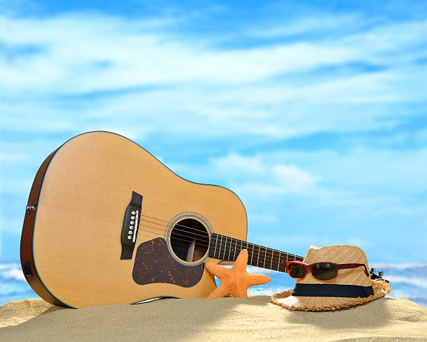 Acoustic guitar on the sandy beach in summer with blue sea and sky