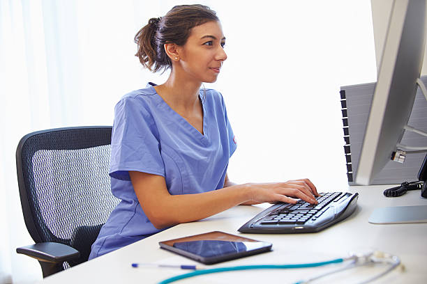 feminino médico no escritório trabalhando no computador - uniforme hospitalar - fotografias e filmes do acervo