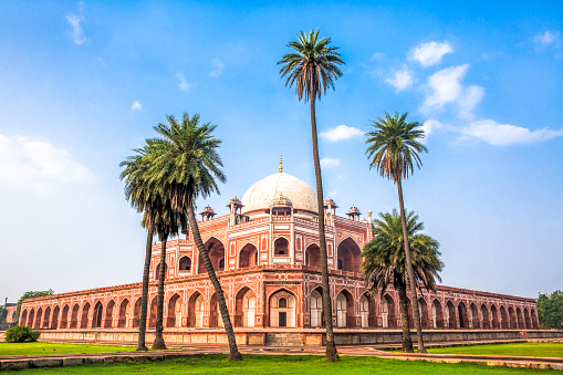 Daytime view of Humayun’s Tomb, fine example of Great Mughal architecture, UNESCO World Heritage, Delhi, India. Birds flying in the blue sky.
