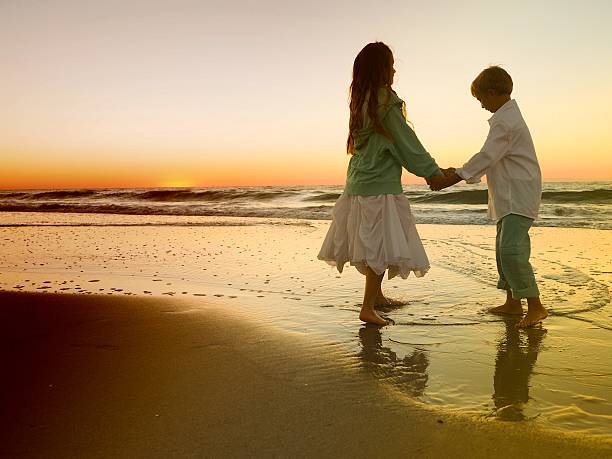 istock Boy And Girl Playing Ocean Sunrise 489343340