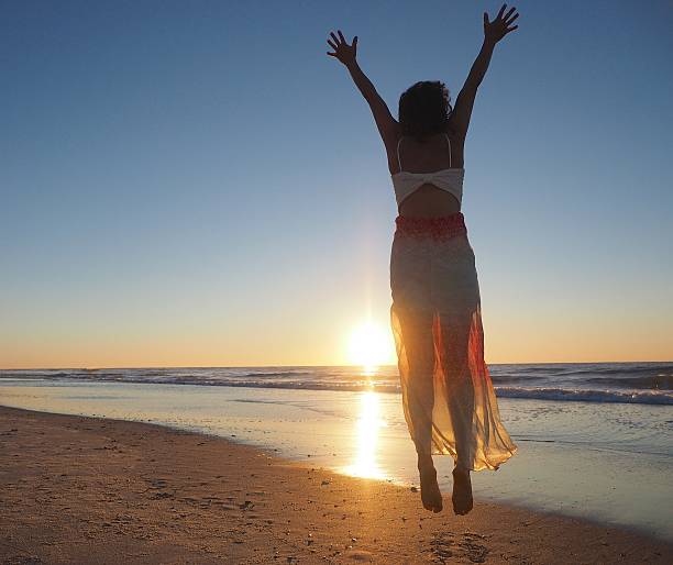 istock Woman In Dress Jumping On Beach 489343992