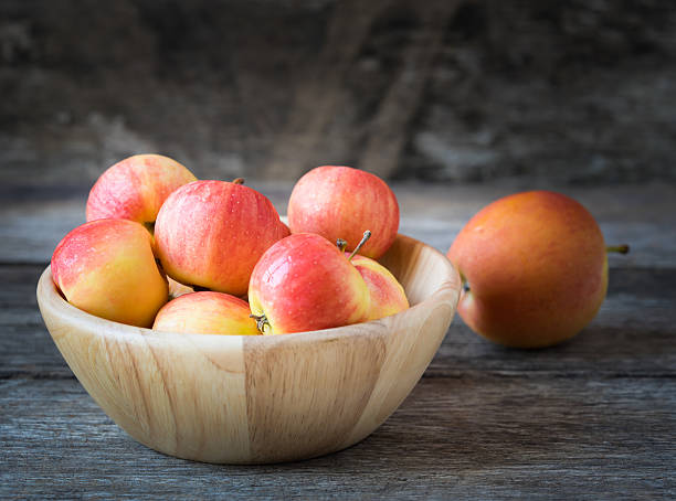 istock Apples in a wood bowl on wooden background. 489344128