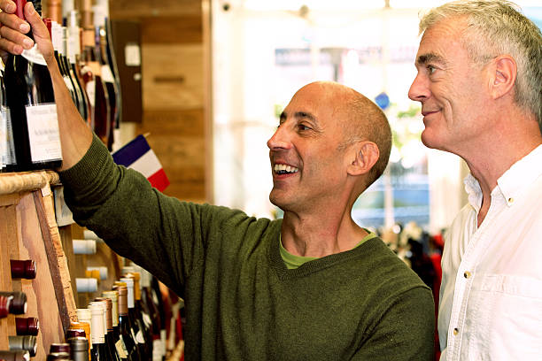 Senior Gay Male Couple Buying French Wine to Celebrate stock photo