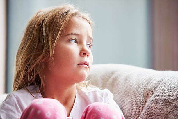 Physically Abused Child At Home Sitting On Sofa