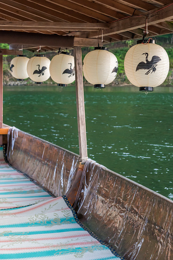 Paper lanterns with a cormorant logo on them hanging from the roof of a tourist boat