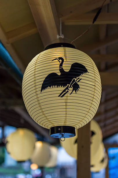 A paper lantern with a cormorant logo on it hanging from the roof of a tourist boat