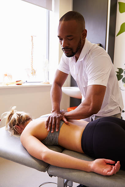 Physiotherapist Giving Female Patient Massage In Hospital Physiotherapist Giving Female Patient Massage In Hospital black male massage stock pictures, royalty-free photos & images