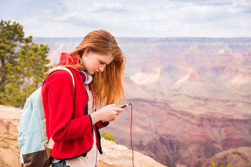 A teenage girl fiddles with her smartphone while being completely oblivious to the scenery at the Grand Canyon National Park in Arizona.