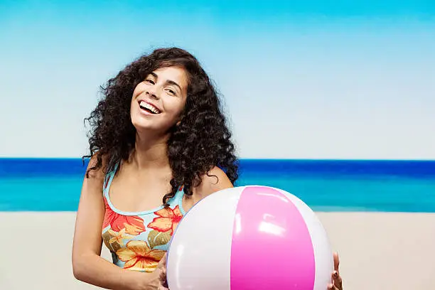 Happy young woman standing in beach with beachballhttp://www.twodozendesign.info/i/1.png