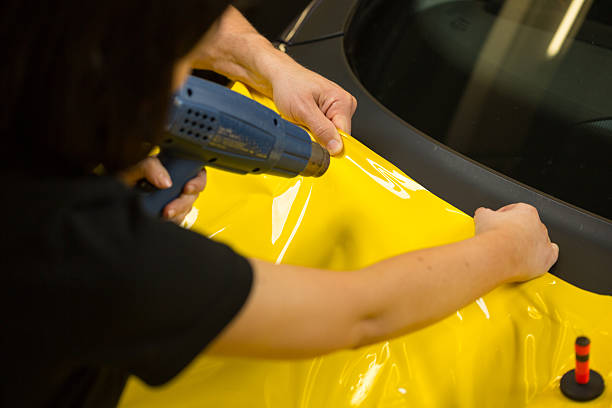 auto packungen mit heißluftpistolen, um vinyl- folie - einwickeln stock-fotos und bilder