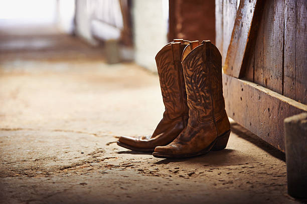Another day done Shot of a pair of cowboy boots in a barn boot photos stock pictures, royalty-free photos & images