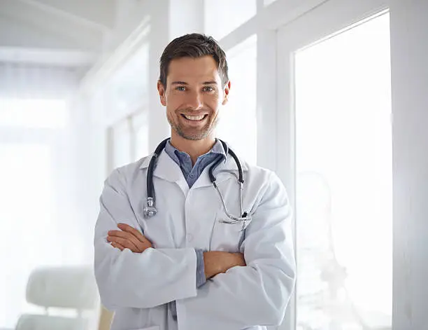 Portrait of a handsome male doctor standing with his arms folded