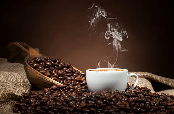 Photo of White cup with coffee beans on dark background