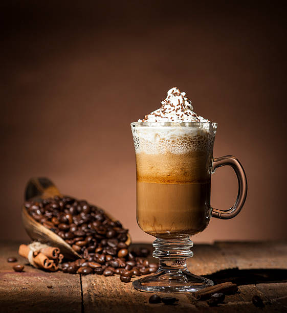 Glass cup with coffee beans Transparent  glass coffee cup and wooden spoon with coffee beans on wooden and brown background. mocha stock pictures, royalty-free photos & images