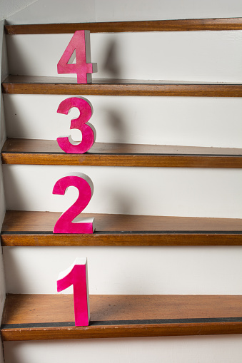 red white cardboard numbers on a wooden staircase Number 4 going down to 1