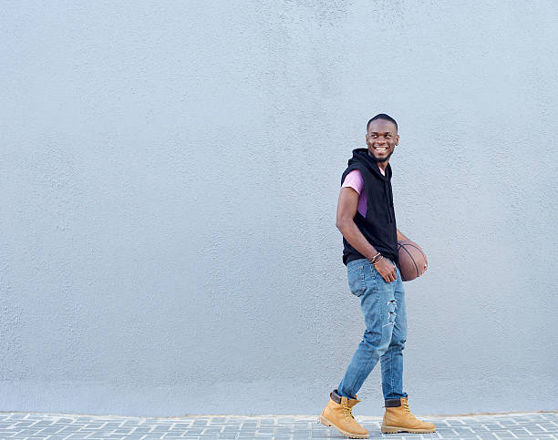 istock Happy young man walking on sidewalk with basketball 489379306