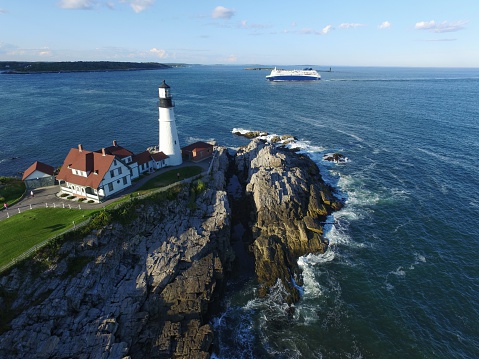 Aerial view of Historic Portland Head Light Lighthouse, Cape Elizabeth, Rocky Coast, Maine. Waves breaking on rocks overhead view Photographed using camera attached to DJI Phantom 3 Professional Drone.