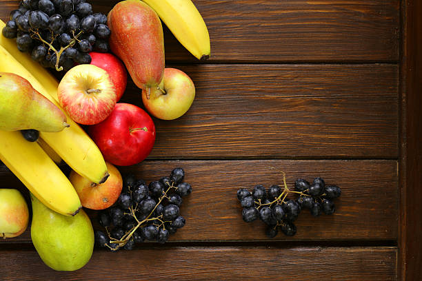 istock various fruits (apples, pears, bananas, grapes) on a wooden background 489384100
