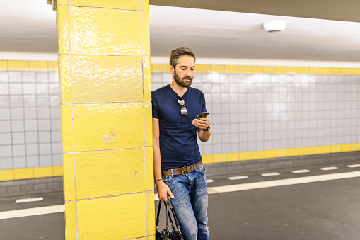 Young man with phone waiting for subway train