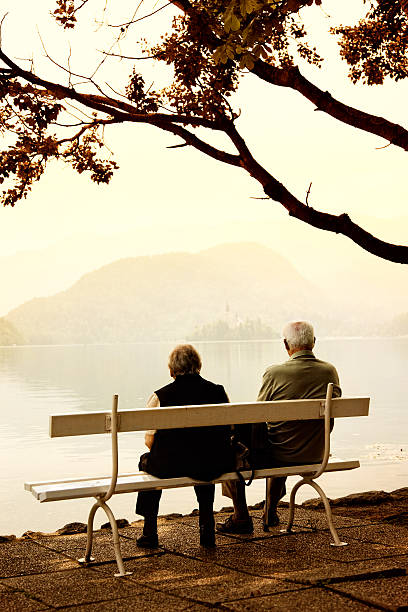 istock senior couple siting on bench at lake shore 489426677