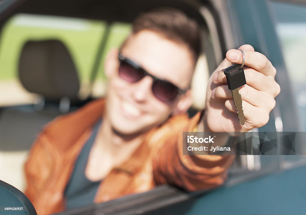 Young man showing car keys - Stock Image Man sitting inside car and showing keys to new car Adult Stock Photo