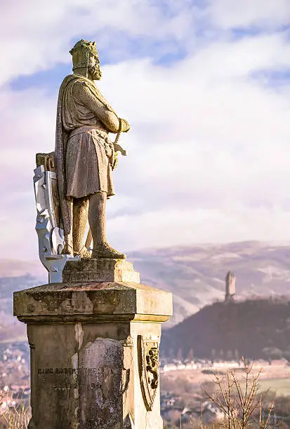A 19th Century statue of Robert the Bruce (1274 - 1329) located in Stirling, Scotland, with the Wallace Monument in the background.