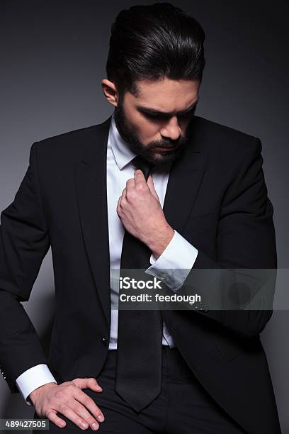Young Fashion Man Looks Down And Fixes Tie Stock Photo - Download Image Now - Men, Tuxedo, Black Color