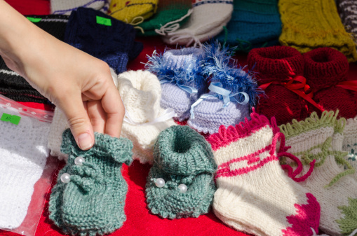 Hand take colorful homemade wool hand-knit knitted warm cozy baby shoes sold market fair.