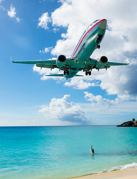 Maho Bay, St Maarten, Netherlands Antilles - November 15, 2013: A man in the sea reaches toward an American Airlines Boeing 737-823 about to land at Princess Juliana International Airport in St. Maarten.