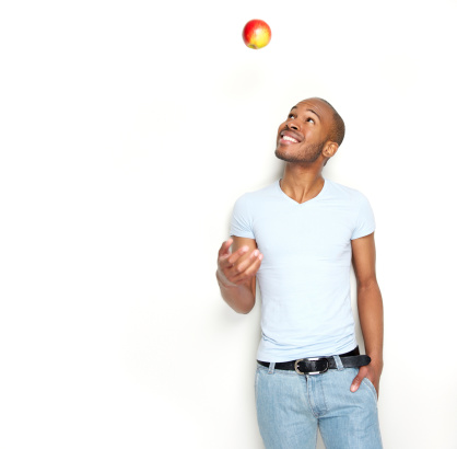 Healthy young man throwing apple in the air