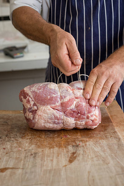 istock Butcher tying up a joint of ham 489430310