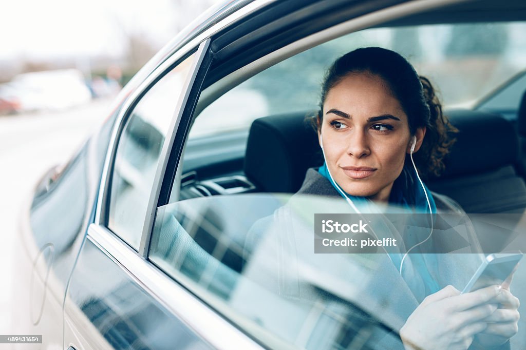 Woman in car Young woman on the back seat with smart phone and headphones Car Stock Photo