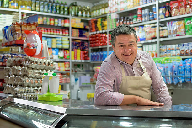 negoziante in un negozio di alimentari locale - sales clerk store sales occupation retail occupation foto e immagini stock