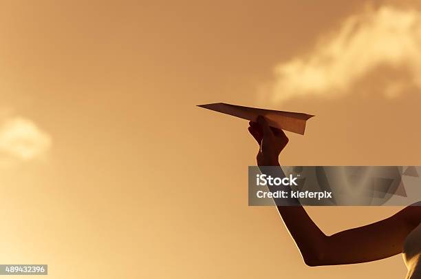 Giovane Donna Preparando A Lanciare Un Aeroplano Di Carta - Fotografie stock e altre immagini di Aeroplano di carta