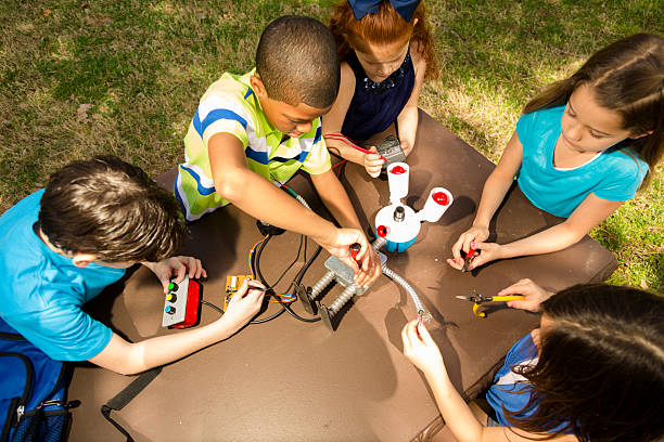 Little engineers!  Ethnic elementary children collaborate on 'robot' they created.