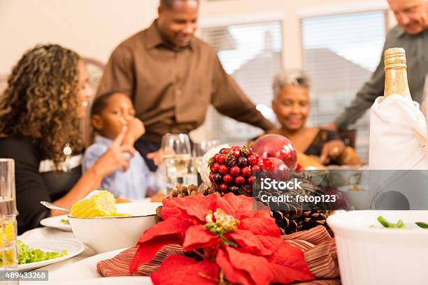 Family Gather Around The Dinner Table At Christmas Time Stock Photo - Download Image Now