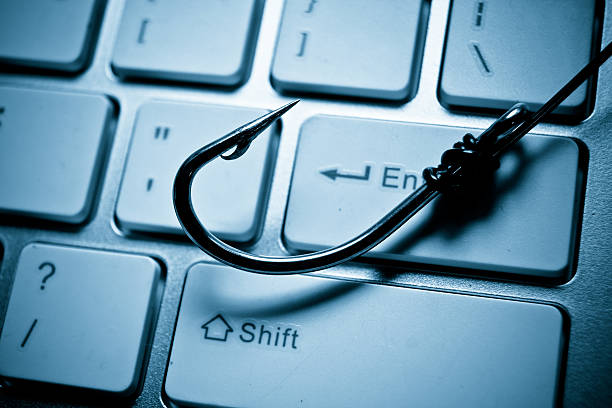 phishing a fish hook on computer keyboard representing phishing attack on computer system hook equipment photos stock pictures, royalty-free photos & images
