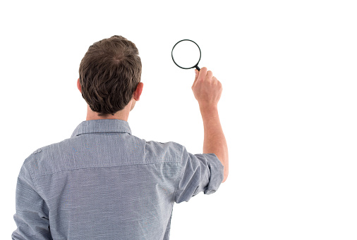 Casual business man holding a magnifying glass - isolated over white background