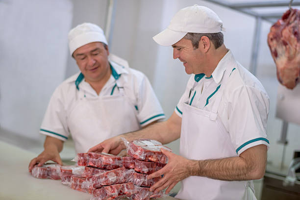 Butchers working at the butchery packing meat and looking very happy - small business concepts