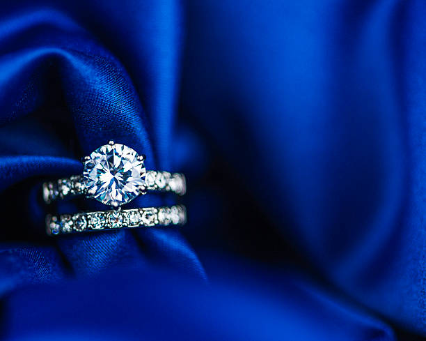 diamond rings on rich satin background - elmas yüzük stok fotoğraflar ve resimler
