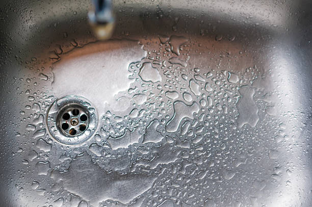 istock Stainless steel sink plug hole close up with water 489481154