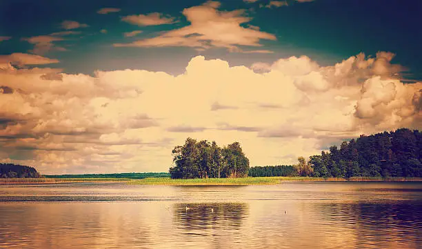 instagram nashville tone Landscape with grass, trees and fluffy clouds reflecting in water surface of lake