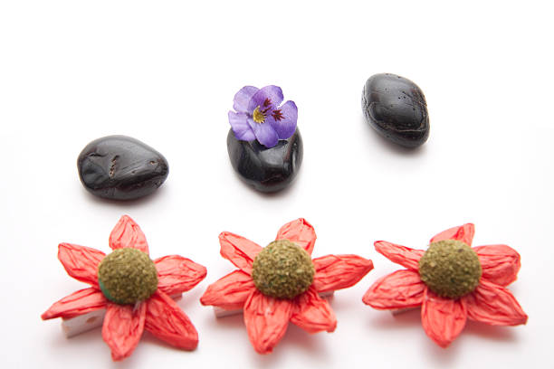Black stones with paper blossom on white background