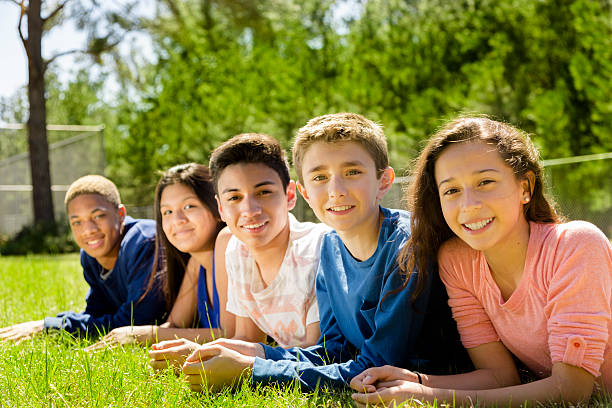 Teenagers: Group of friends hang out together. Park or campus. Group of teenage friends hang out outside together at a local park or school campus. 13 14 years child teenage girls lying down stock pictures, royalty-free photos & images
