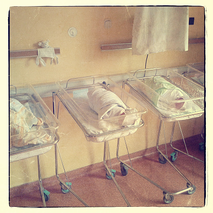 Newborn infants just after birth in hospital's little babies beds. Retro look, instant camera.