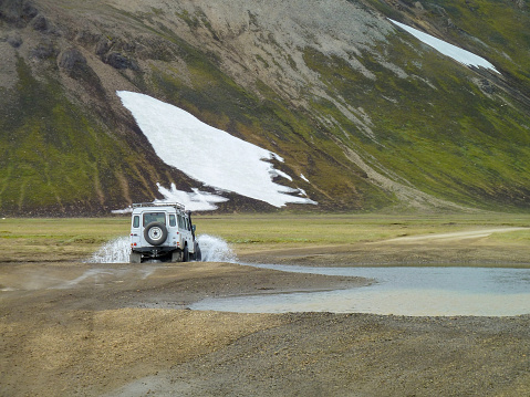wilderness scenery with off-road vehicle crossing a stream in Iceland