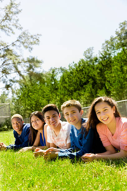 Teenagers: Group of friends hang out together. Park or campus. Group of teenage friends hang out outside together at a local park or school campus. 13 14 years child teenage girls lying down stock pictures, royalty-free photos & images